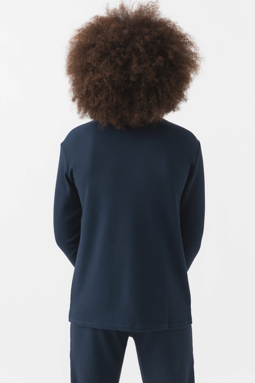 A child with voluminous curly hair, seen from behind, is wearing the Cozy Earth Children's Bamboo Waffle Knit Base Layer Long Sleeve in dark navy. The background is plain white.|Color:Navy