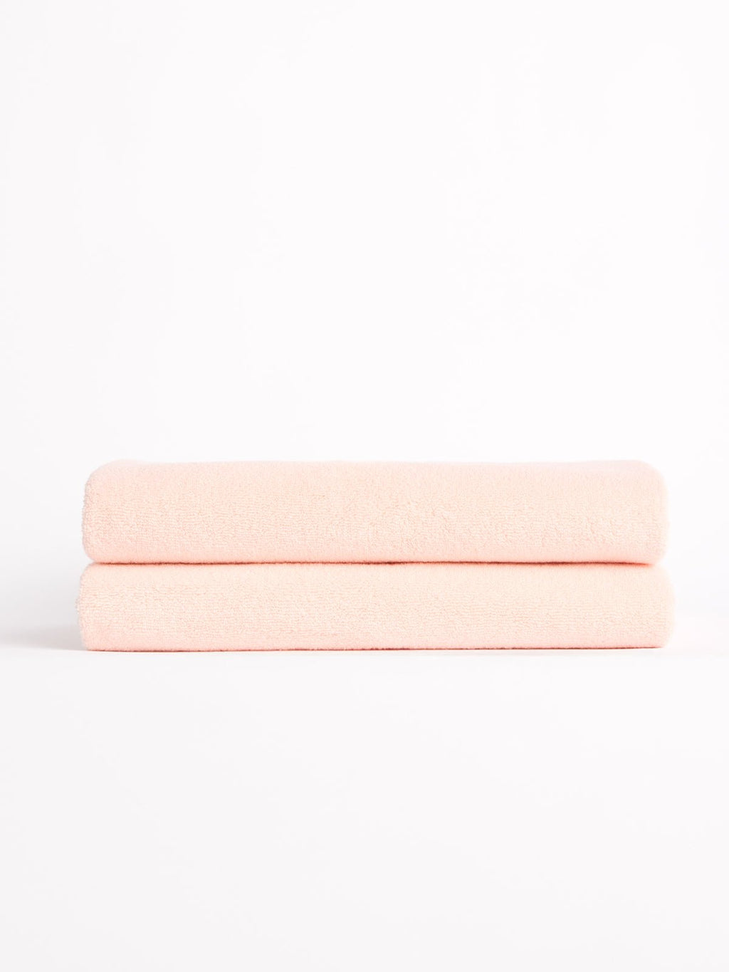 Two Luxe Bath Towels from Cozy Earth, neatly folded in light pink, stacked against a white background. |Color:Blossom