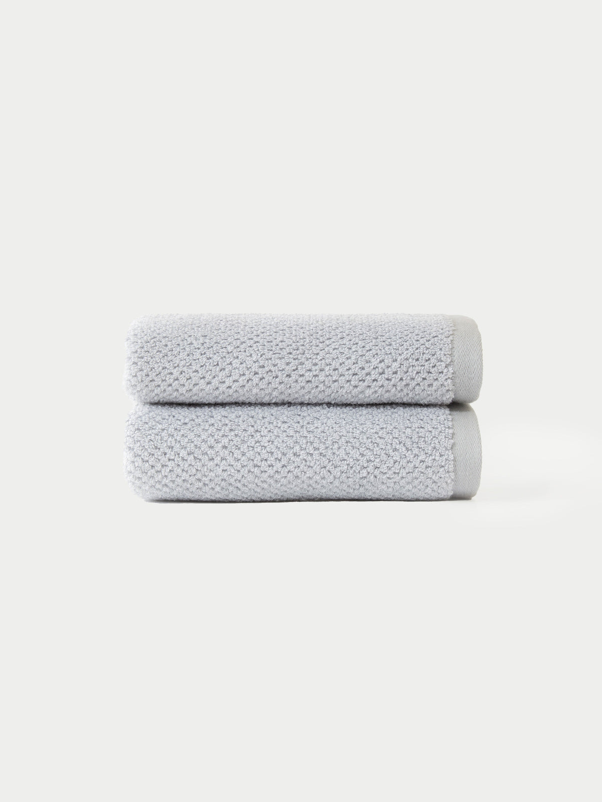 Two Nantucket Bath Towel Set towels by Cozy Earth, neatly folded in light gray and stacked atop each other, displayed against a plain white background.|Color: Heathered Harbor Mist