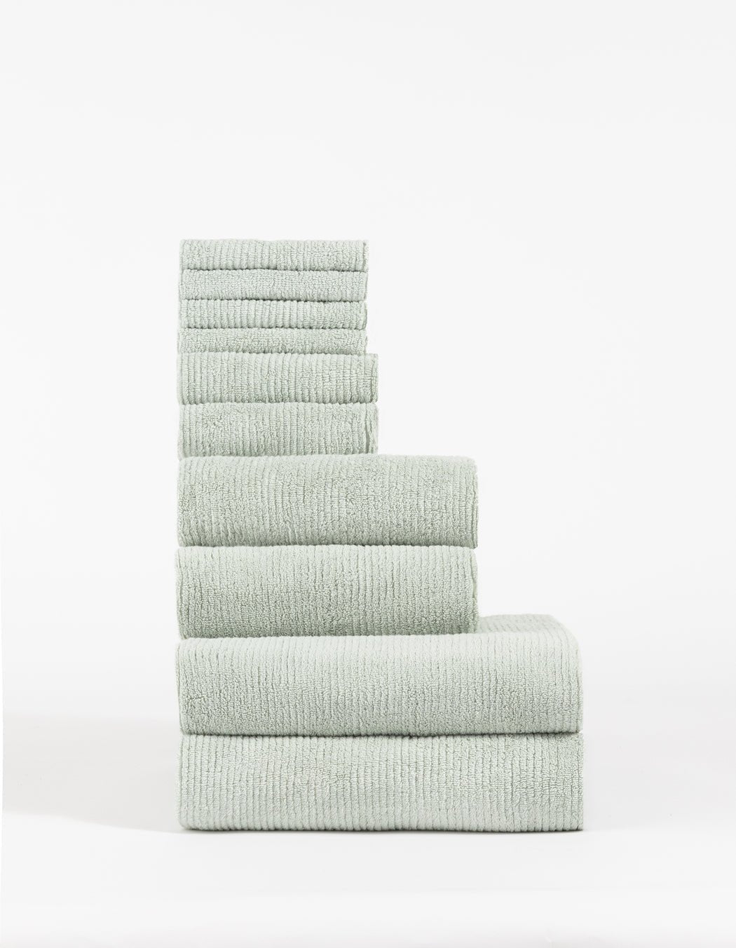 The Cozy Earth Complete Ribbed Terry Bath Bundle features a stack of light gray, ribbed towels in descending size order, arranged neatly against a plain white background.|Color:Laurel