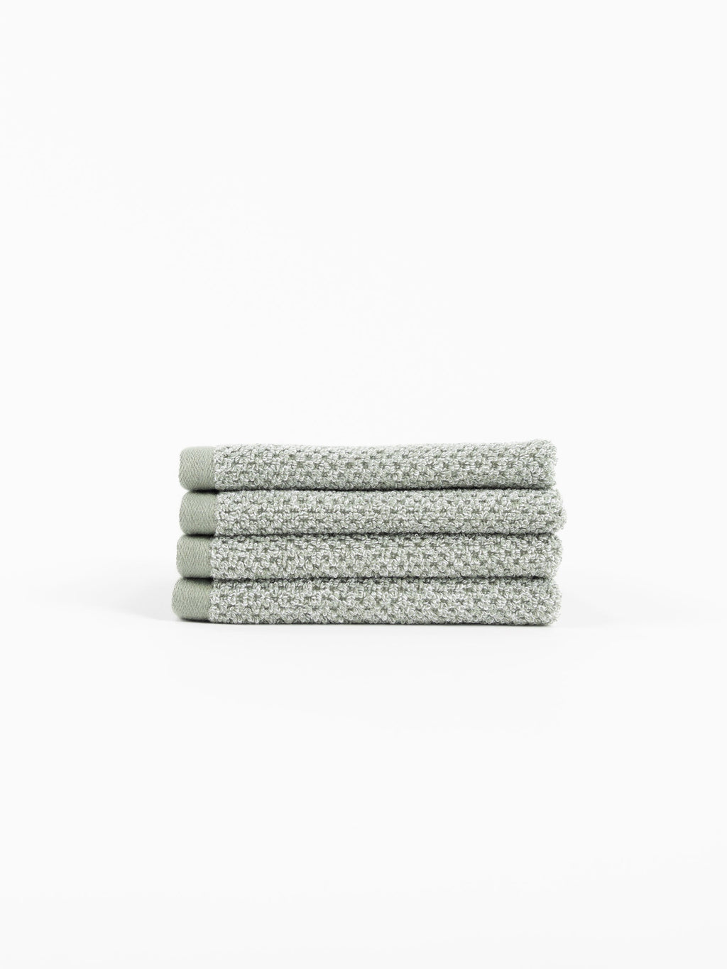 A neatly folded stack of four Cozy Earth Nantucket Bath Towels in textured light gray rests on a white background.|Color:Heathered Sage