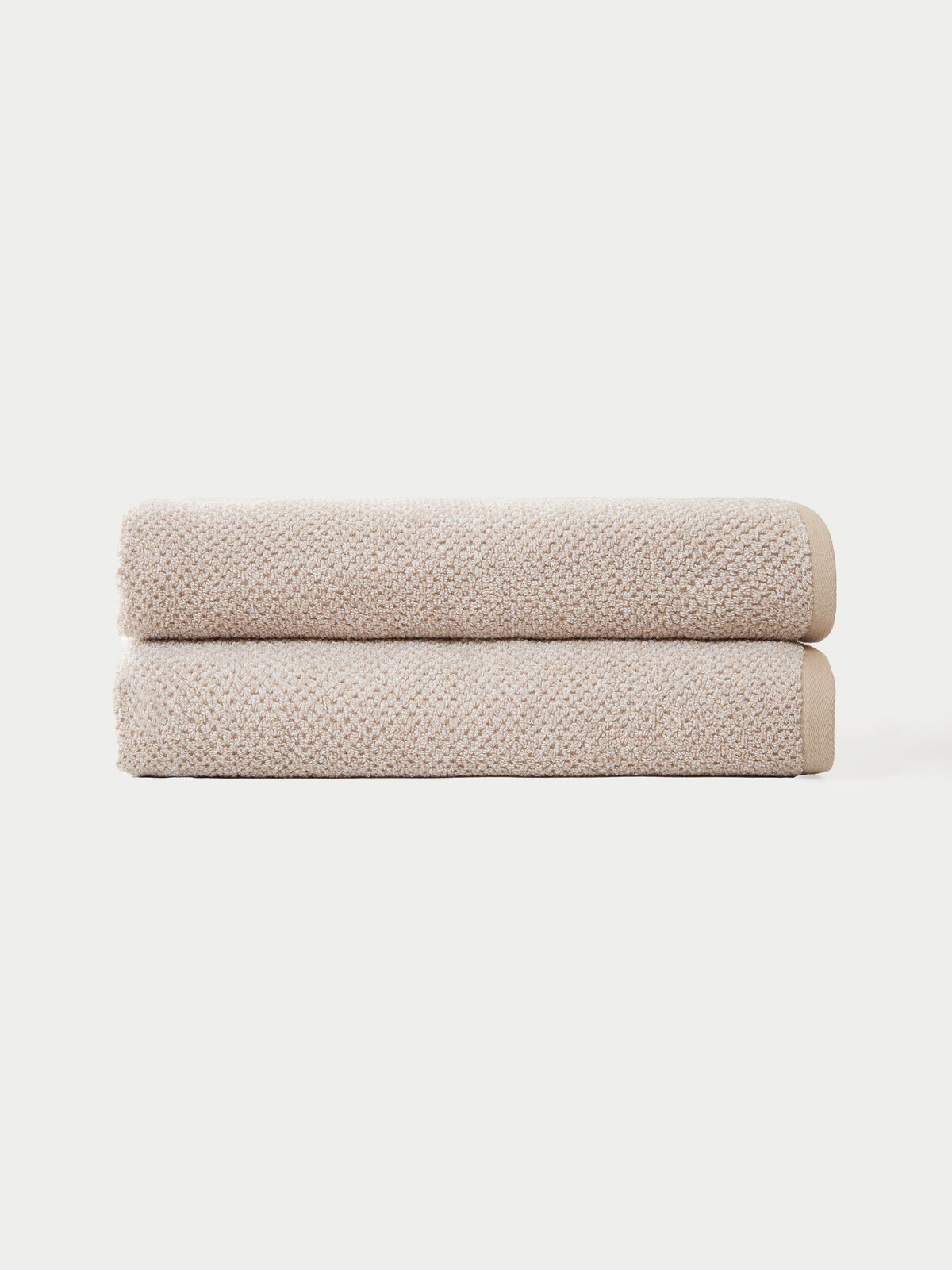 Two neatly folded towels from the Cozy Earth Complete Nantucket Bath Bundle are stacked against a plain white background.|Color:Heathered Sand
