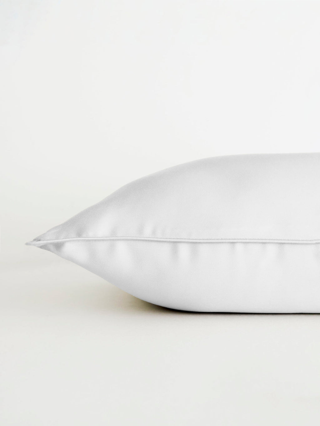 A Bamboo Travel Pillowcase by Cozy Earth is displayed on a white surface, side view against a plain white background, emphasizing its soft texture and smooth finish. |Color:White