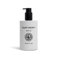 A white bottle of Cozy Earth Body Oil with a black pump dispenser and minimalist black text and logo on the front, containing 207 ml (7 fl oz).