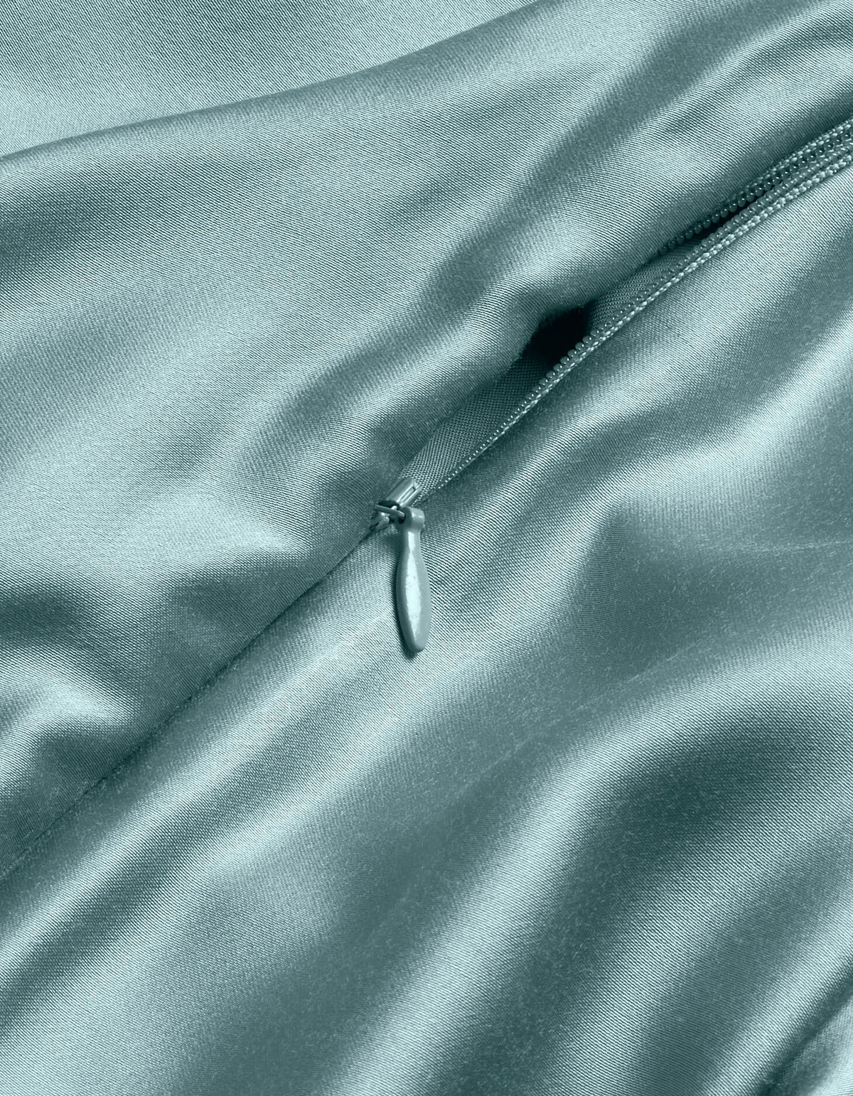 A close-up of the Cozy Earth Bamboo Duvet Cover in light blue shows its shiny, delicate satin texture with a partially unzipped zipper highlighting the smooth, luxurious folds.|Color:River