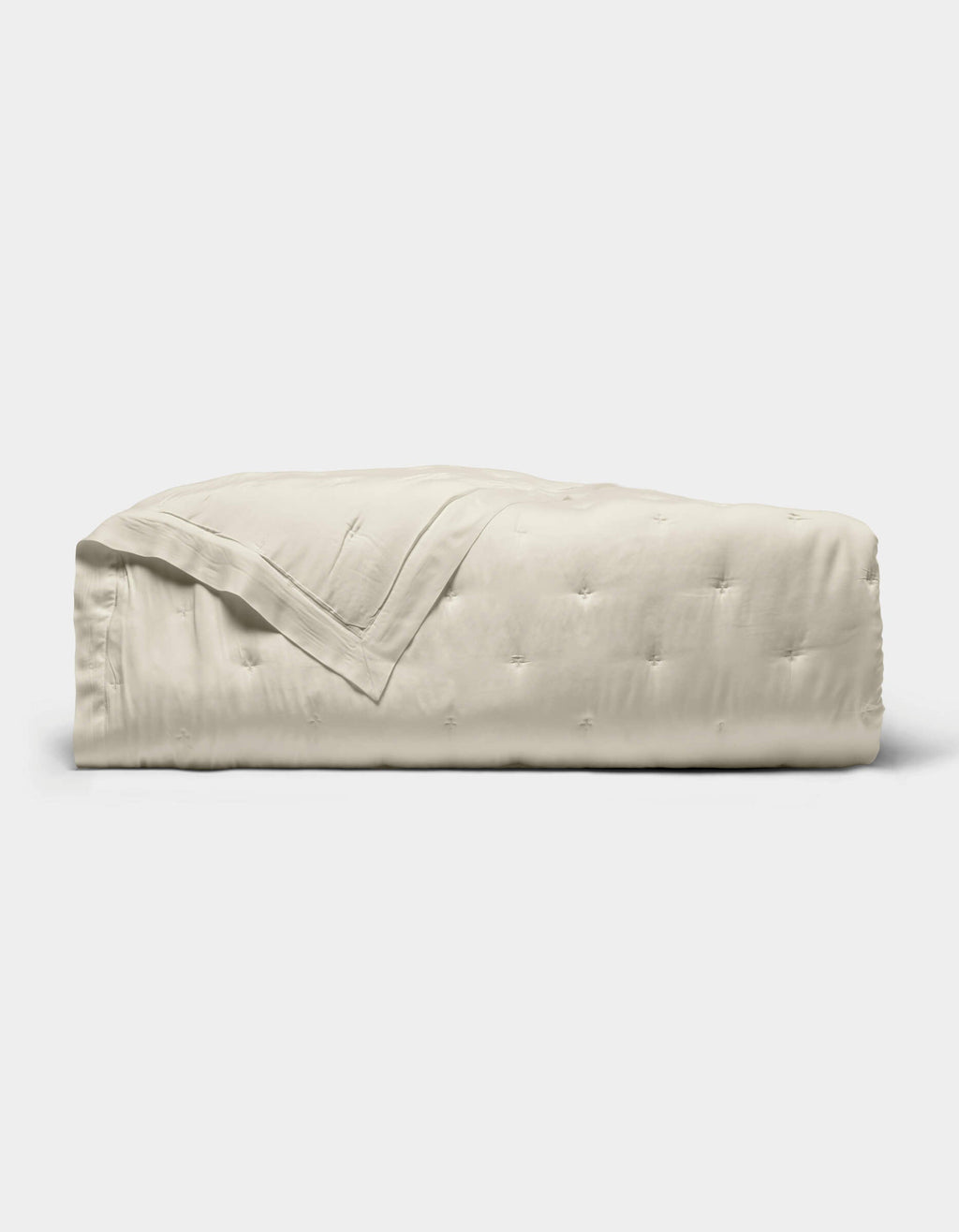 The Cozy Earth Bamboo Quilt, featuring a subtle quilted pattern and light beige color, is neatly folded and displayed against a plain white background.|Color:Oat
