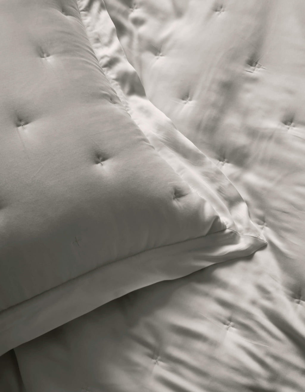 Close-up of two Cozy Earth Bamboo Quilted Shams and a matching comforter, all in smooth, light gray satin fabric with a subtle sheen.|Color:Light Grey