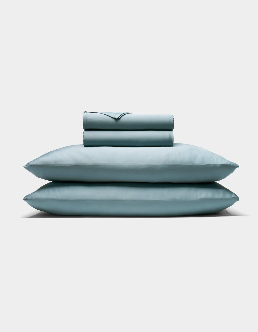The Cozy Earth Bamboo Sheet Set, featuring two pillows and a folded sheet in pale blue, is neatly stacked against a plain white background.|Color:River