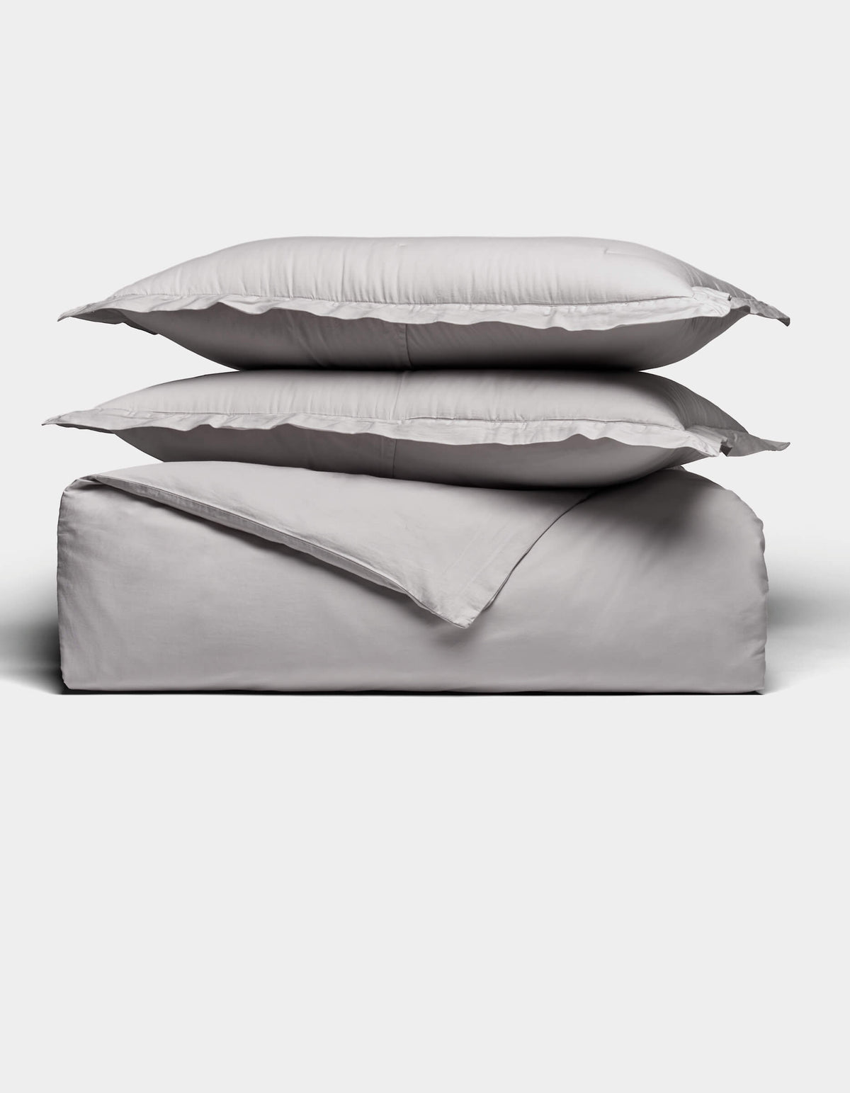 Two gray pillows rest atop a folded Soft-Wash Cotton Duvet Set by Cozy Earth, all neatly arranged against a plain white background.|Color:Dew