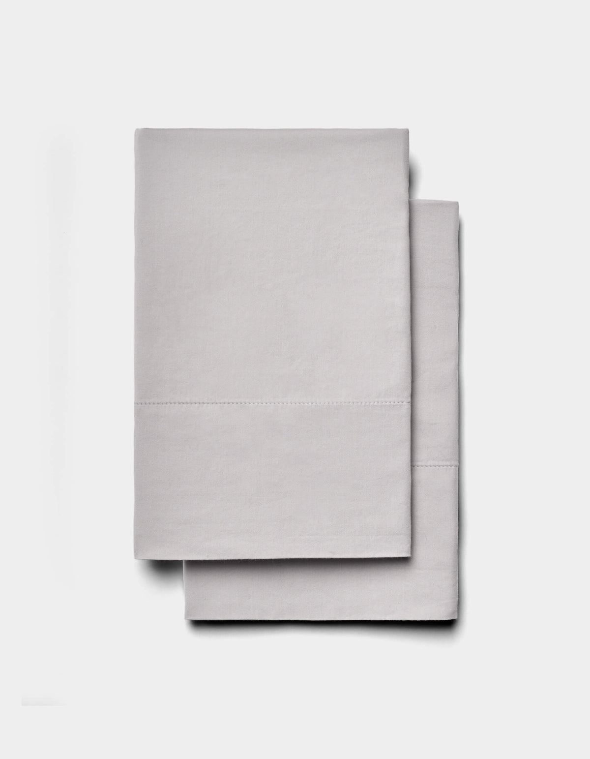 Two neatly folded Soft-Wash Cotton Sheet Sets by Cozy Earth in light gray are stacked on a plain white background.|Color:Dew