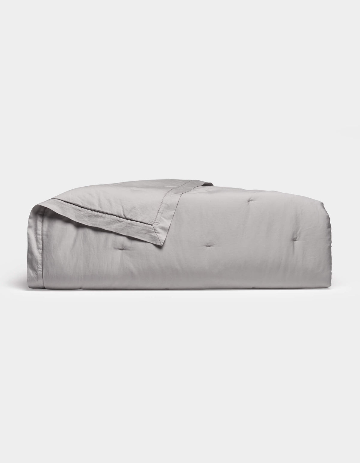 The Cozy Earth Soft-Wash Cotton Quilt in light gray features a subtle quilted pattern and is neatly folded, displayed against a plain white background.|Color:Dew