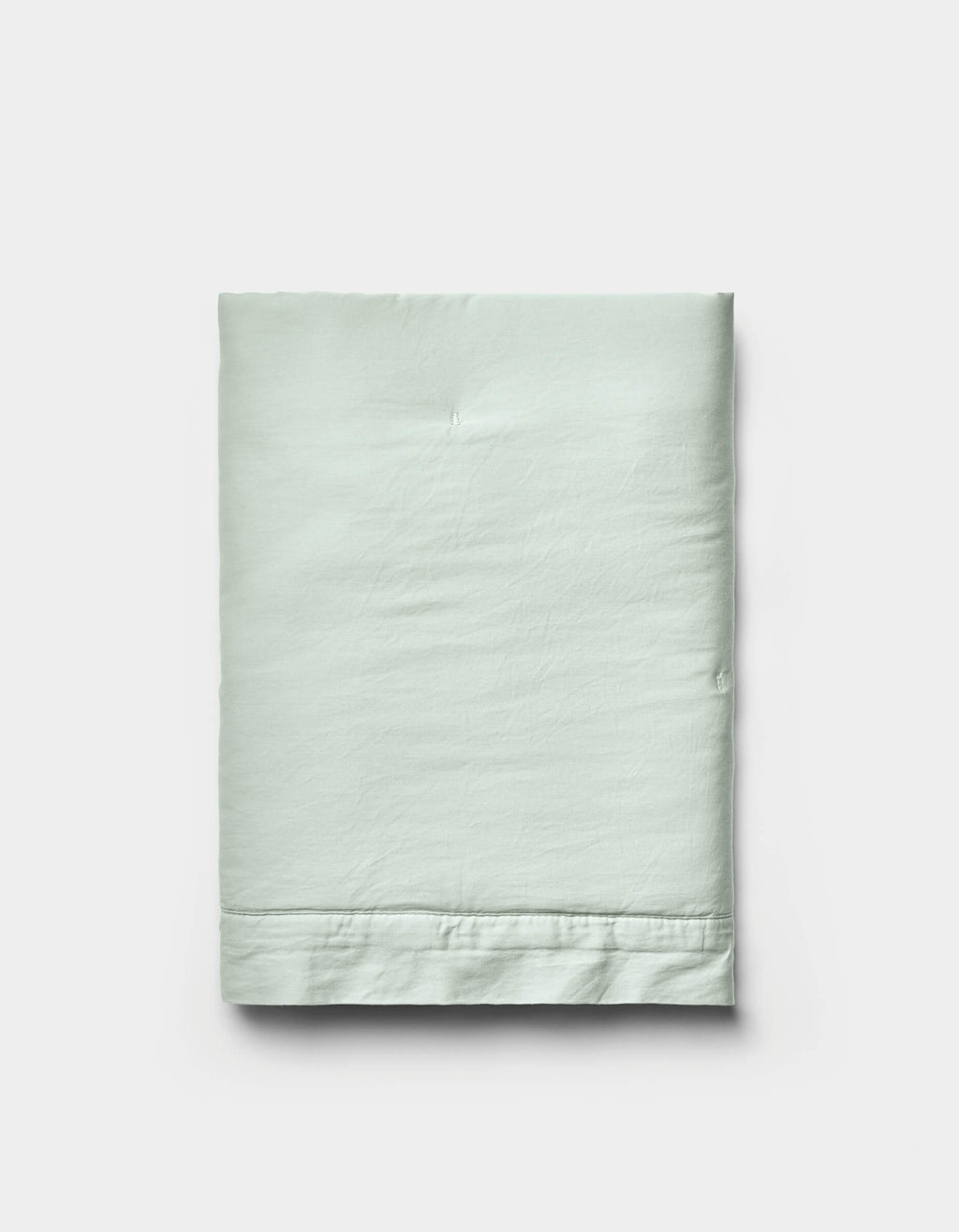 A neatly folded Soft-Wash Cotton Quilted Sham by Cozy Earth in light green is displayed on a plain white background, showcasing its smooth texture and visible stitched hem near the bottom edge.|Color:Laurel