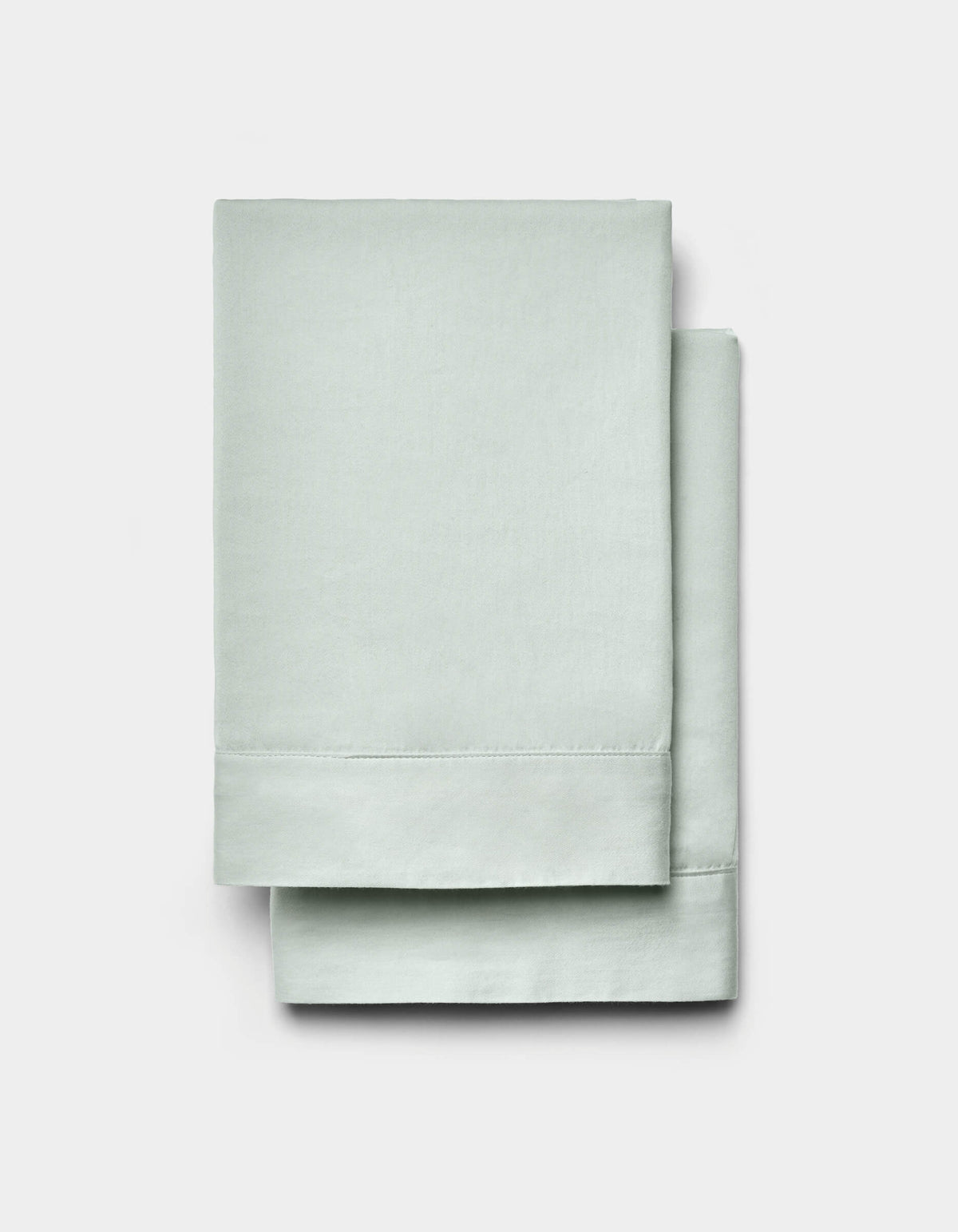 A pair of Cozy Earth Soft-Wash Cotton Shams in light green is neatly folded and displayed against a plain white background.|Color:Laurel