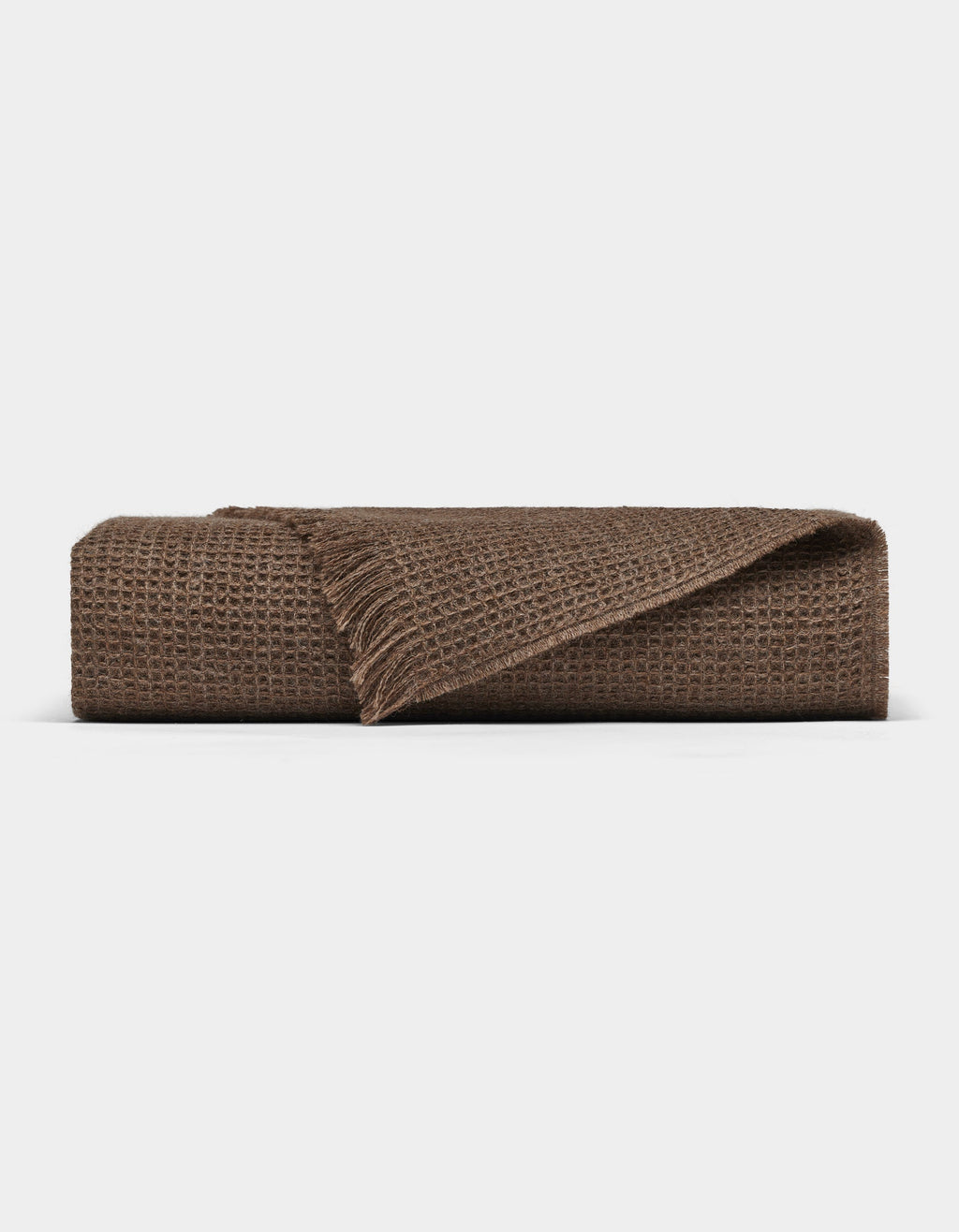 The Cozy Earth Alpaca Waffle Throw features a brown textured waffle weave and fringed edges, shown folded against a plain white background.|Color:Ebony