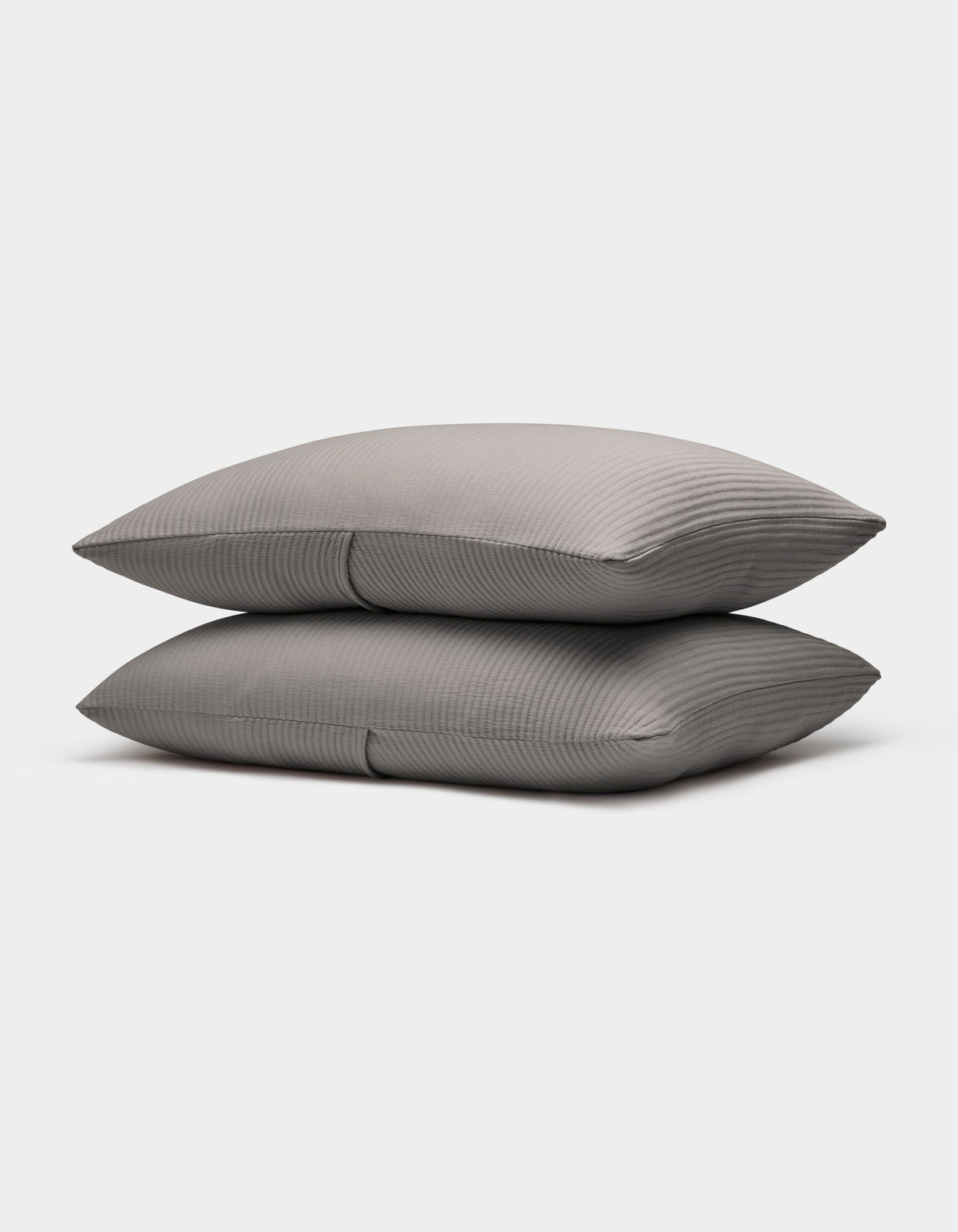 Two neatly stacked Bamboo Coverlet Shams by Cozy Earth in gray with stripes, displayed on a plain white background.|Color:Charcoal