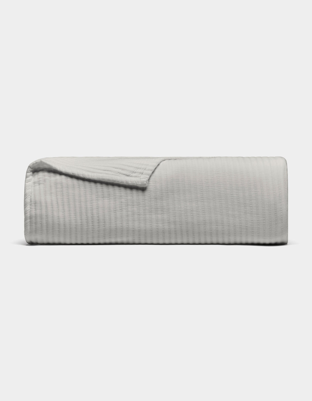 The Cozy Earth Bamboo Coverlet, shown in light gray with a textured design, is neatly folded against a plain white background. A corner is turned down to display its soft material.|Color:Light Grey