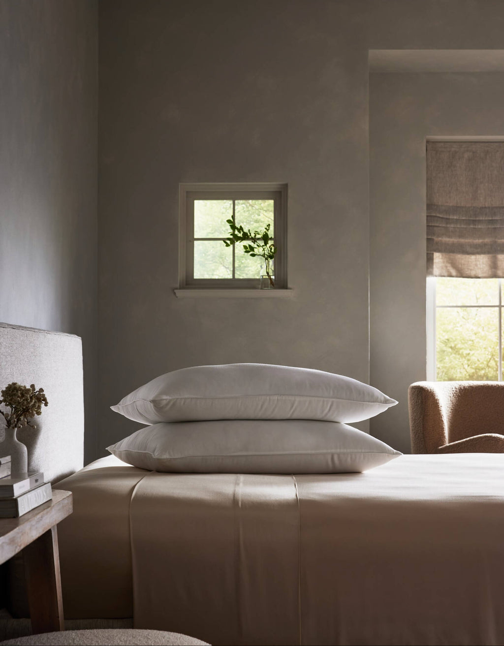 A serene, minimalist bedroom in neutral tones features a neatly made bed with the Cozy Earth Down Alternative Insert Bundle and two stacked white pillows, softly illuminated by daylight near a window with a glass vase of greenery.|Filling:Standard