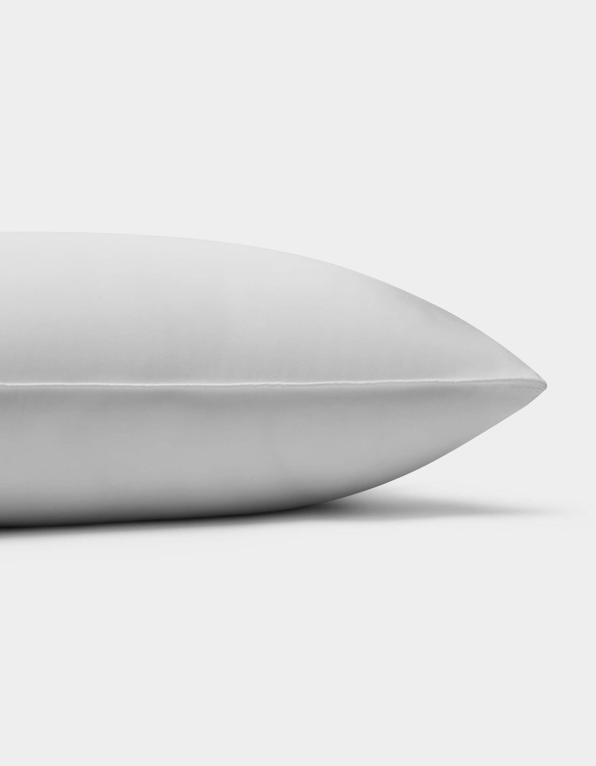 A close-up side view of the Cozy Earth Down Alternative Insert Bundle pillow on a white background, highlighting its smooth, clean surface and pointed end.|Filling:Standard