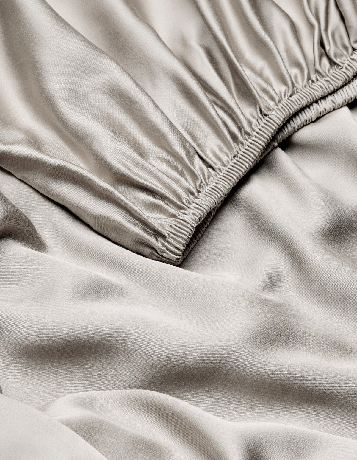 Close-up of Cozy Earth Bamboo Fitted Sheet in light beige, highlighting its smooth, shiny texture with gentle folds and ruching near the seam.|Color:Dove Grey