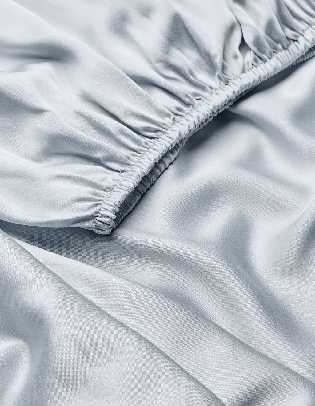 Close-up of Cozy Earth Bamboo Fitted Sheet in light blue, featuring gathered, ruched stitching on one edge for soft folds and a smooth, silky sheen.|Color:Shore