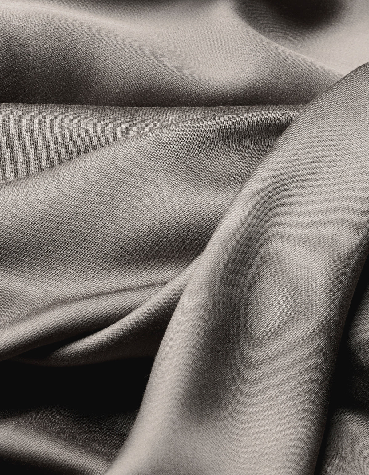 Close-up of Cozy Earth's Bamboo Sheet Set reveals smooth, shiny silver-gray fabric with soft folds and flowing texture, offering a luxurious and elegant look.|Color:Charcoal