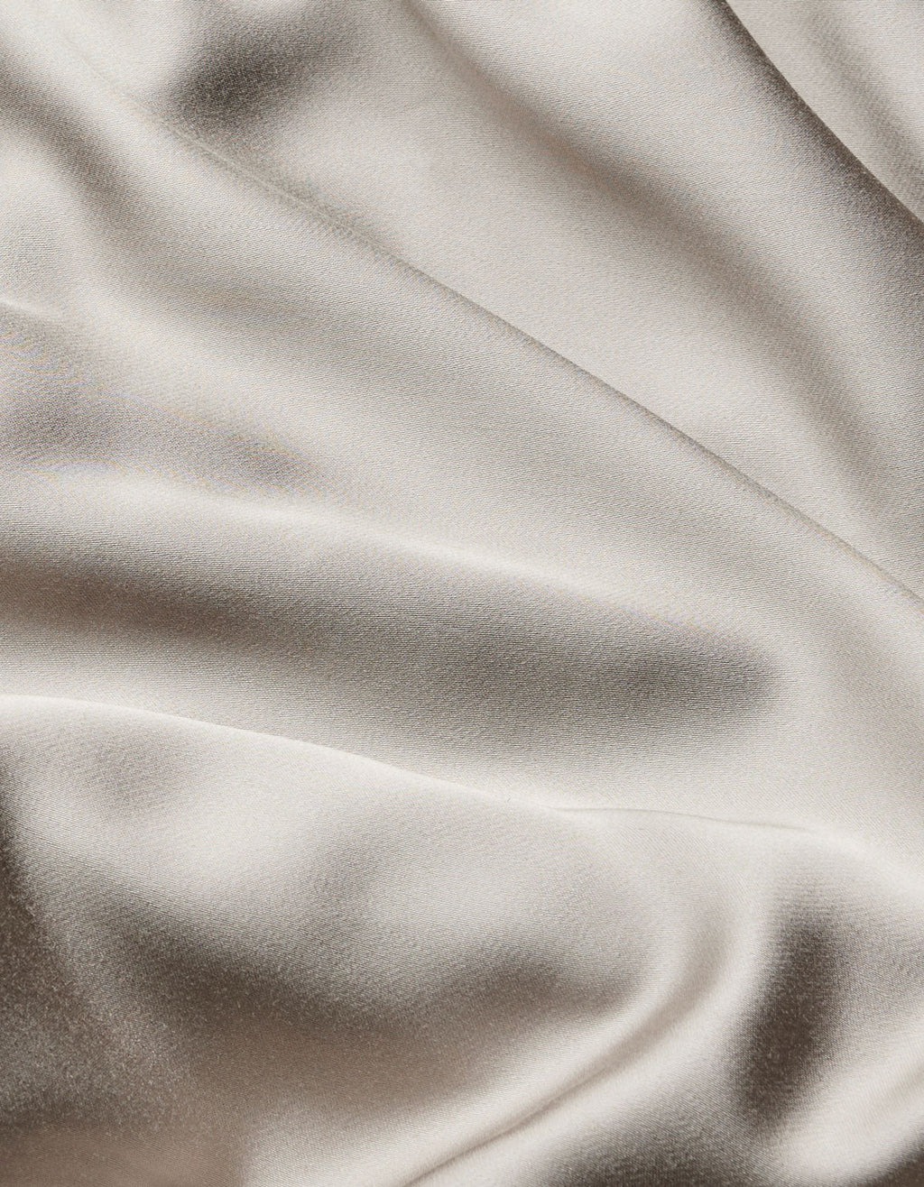 The Bamboo Flat Sheet by Cozy Earth features smooth, cream-colored satin fabric with gentle, flowing folds and a soft sheen that beautifully reflects light.|Color:Dove Grey