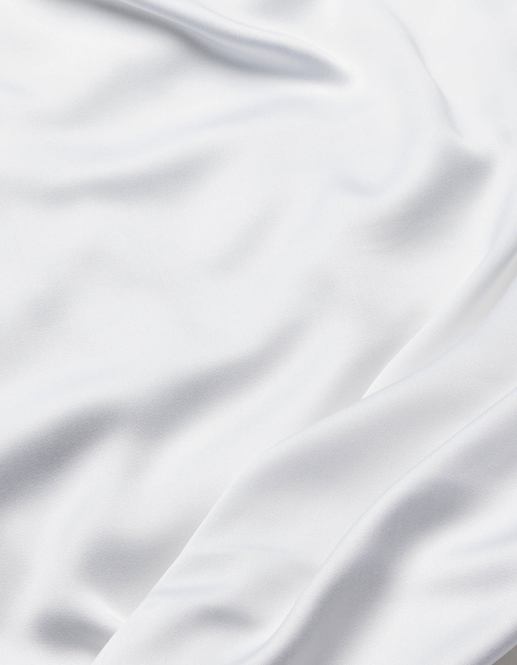 The Cozy Earth Bamboo Sheet Set features smooth white fabric with soft folds and flowing creases, offering a silky, elegant texture.|Color:White