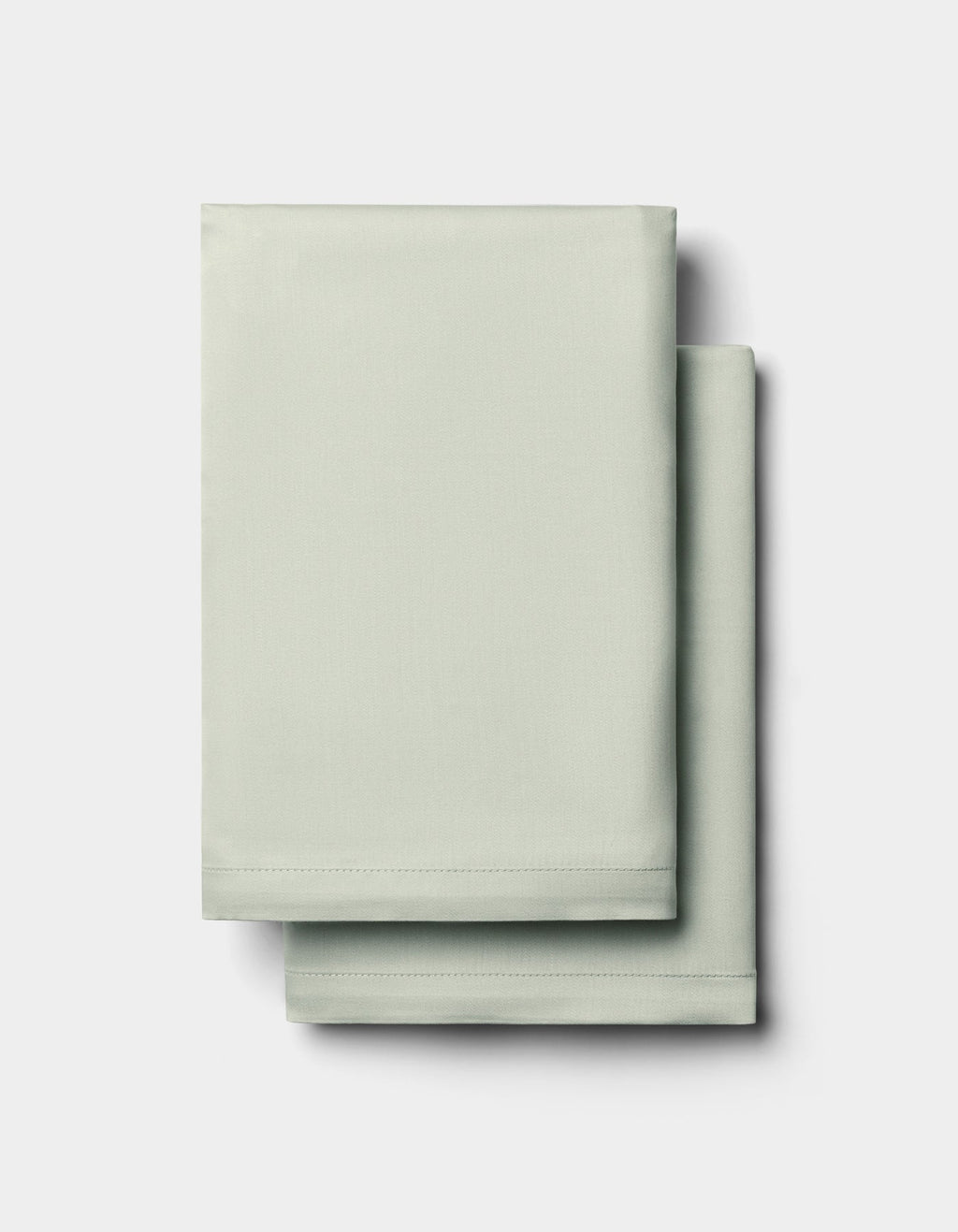 Two neatly folded Cozy Earth Bamboo Pillowcases in light green are stacked on top of each other against a plain white background.|Color:Laurel