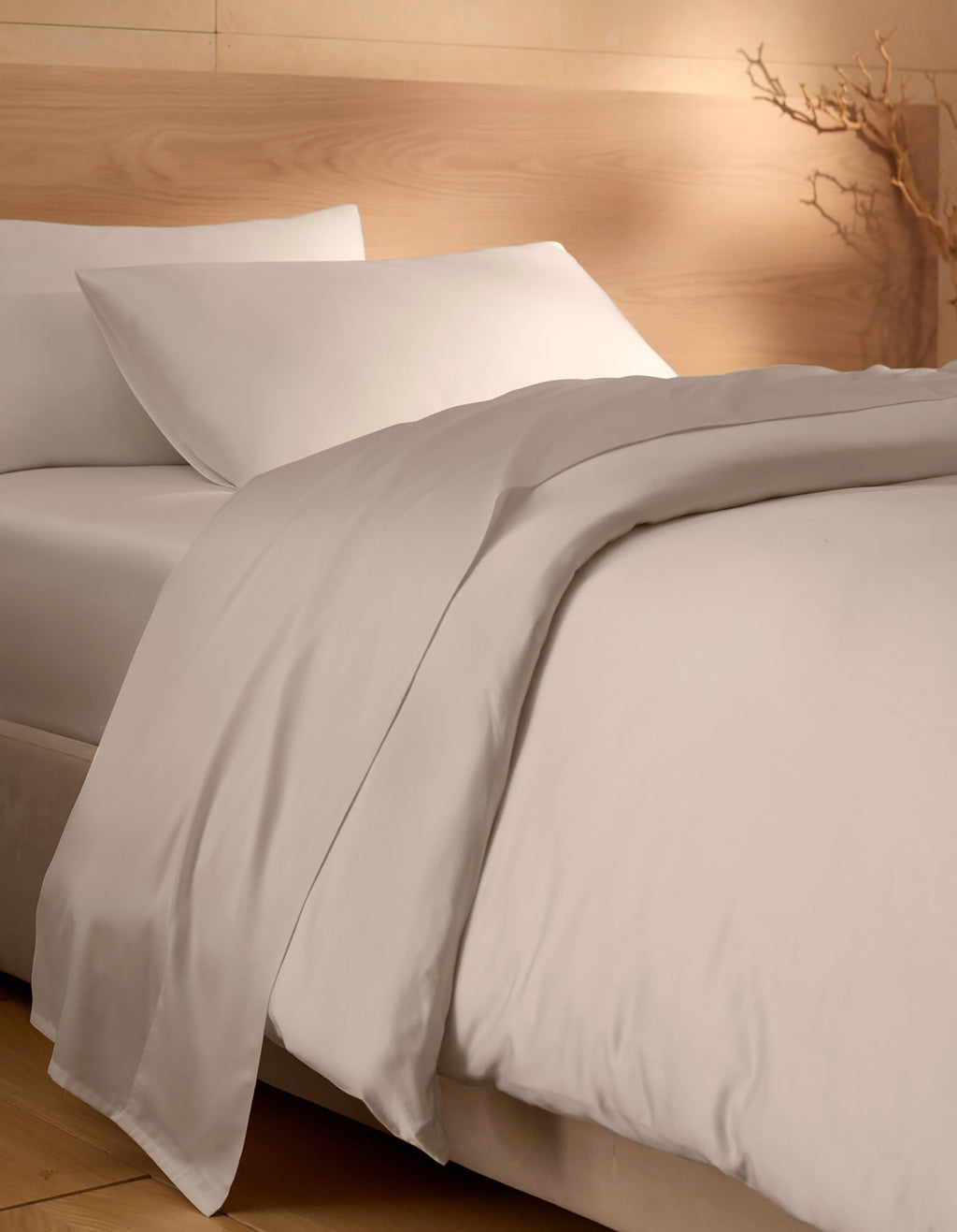 A neatly made bed featuring Cozy Earth's Bamboo Duvet Cover; beige walls, natural wood accents, and a dried branch in the corner create a calm, minimalist atmosphere.|Color:White