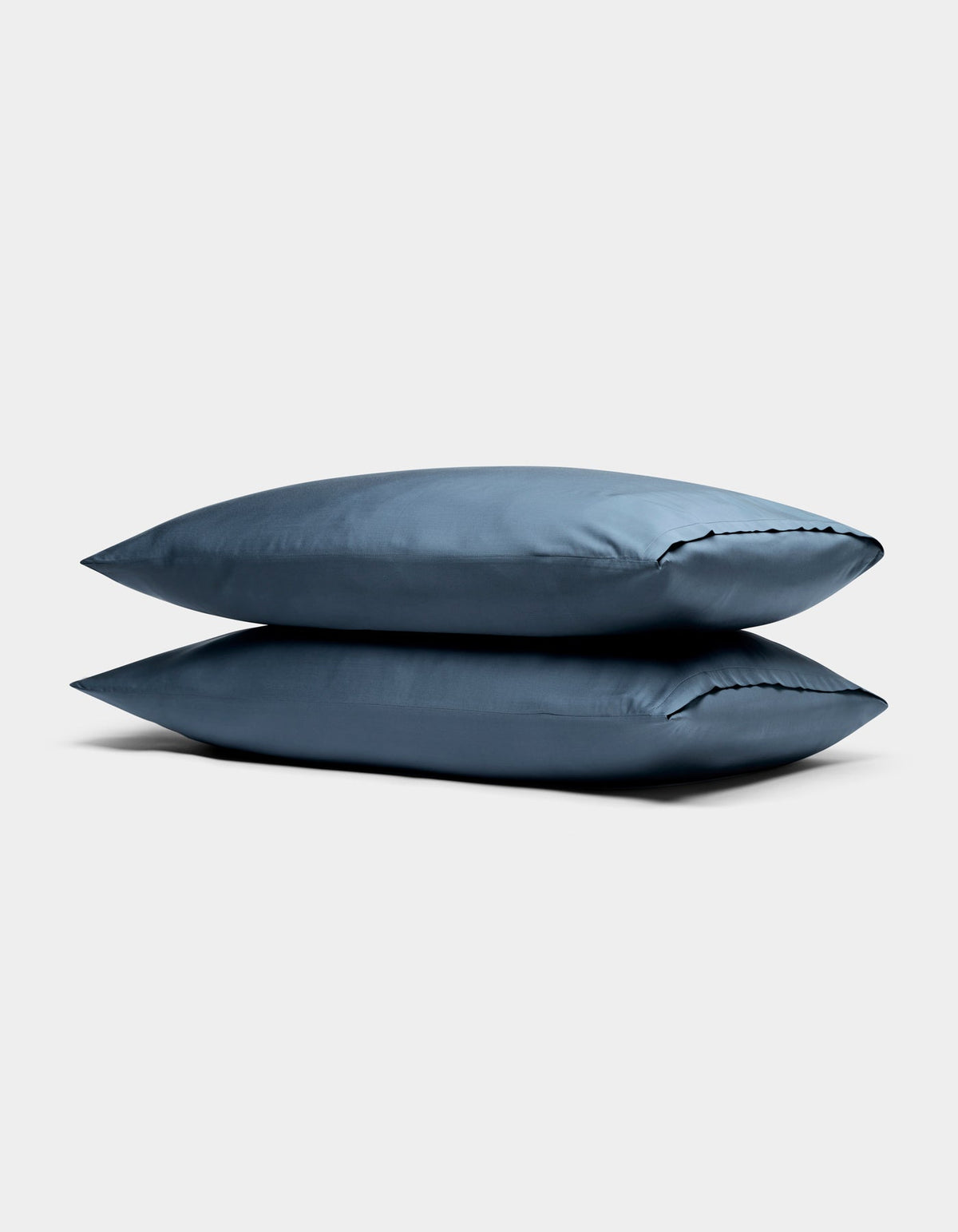 Two Cozy Earth Bamboo Pillowcases in blue are stacked against a plain, light gray background.|Color:Pacific Blue