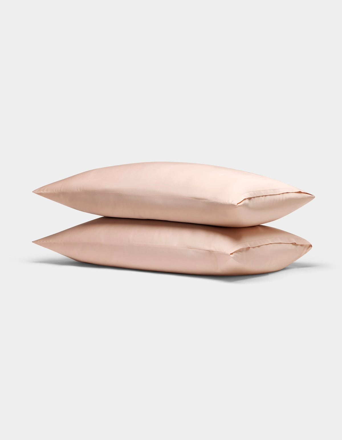 Two light pink Cozy Earth Bamboo Pillowcases are stacked neatly atop each other against a plain, light gray background.|Color:Peony