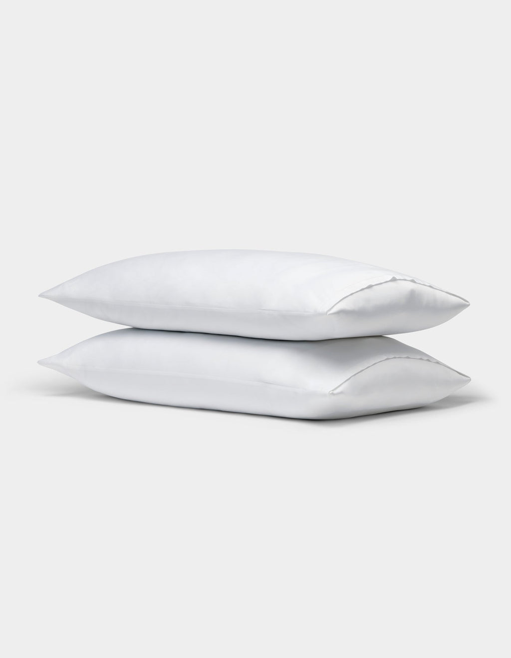 Two Cozy Earth Bamboo Pillowcases, plain white, are stacked on top of each other against a light gray background. |Color:White