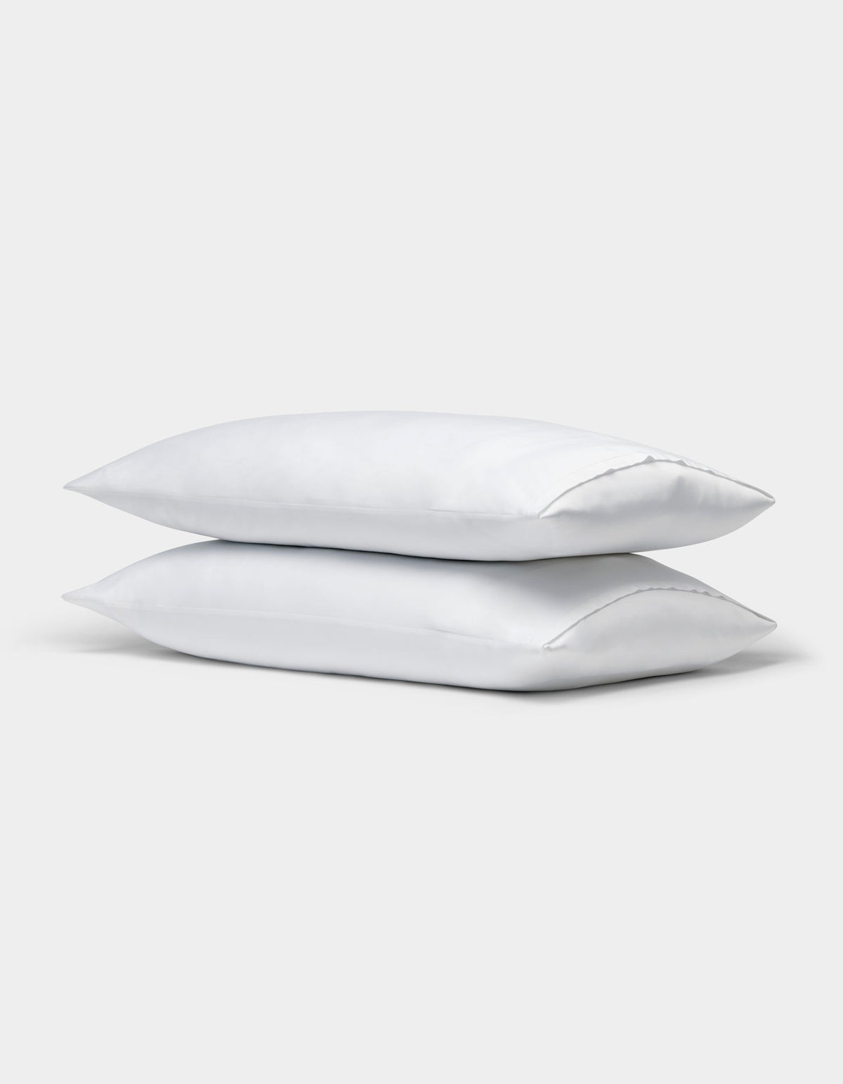 Two Cozy Earth Bamboo Pillowcases, plain white, are stacked on top of each other against a light gray background. |Color:White