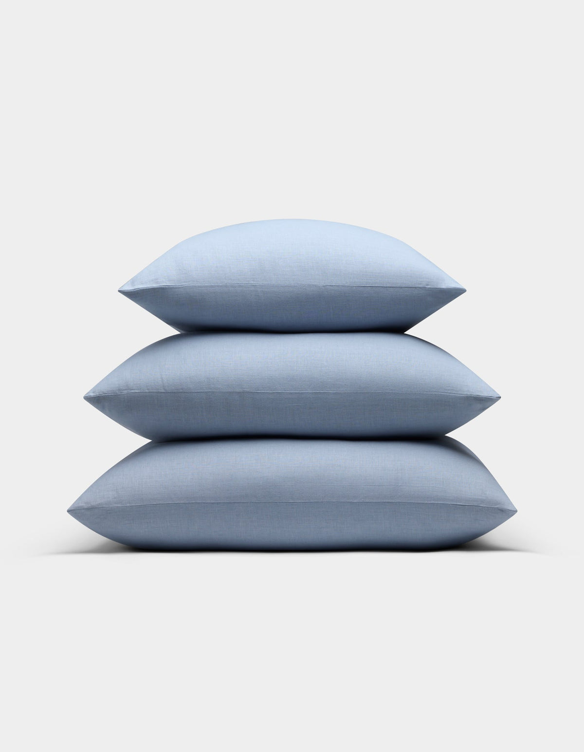 Three Cozy Earth Linen Throw Pillows in light blue are neatly stacked on top of each other against a plain white background.|Color:Breeze |Size:24" x 24"