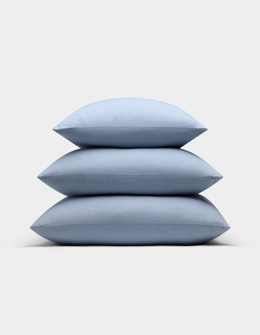 Three Cozy Earth Linen Throw Pillows in light blue are neatly stacked against a plain light gray background.|Color:Breeze |Size:20" x 20"