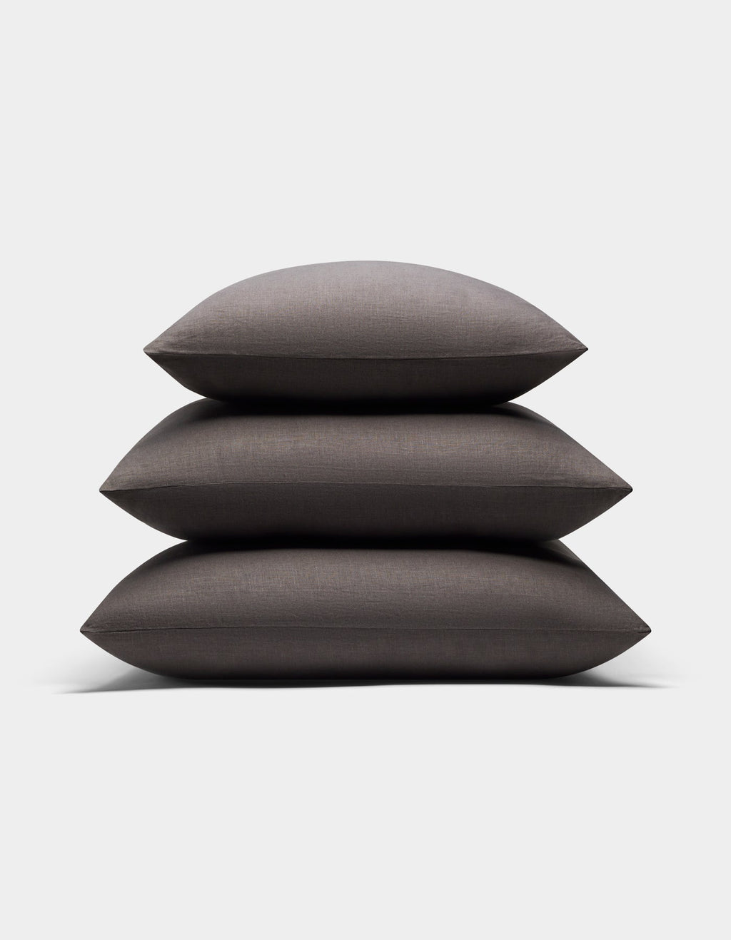 Three Cozy Earth Linen Throw Pillows in dark gray are neatly stacked together against a plain white background.|Color:Coal|Size:20" x 20"