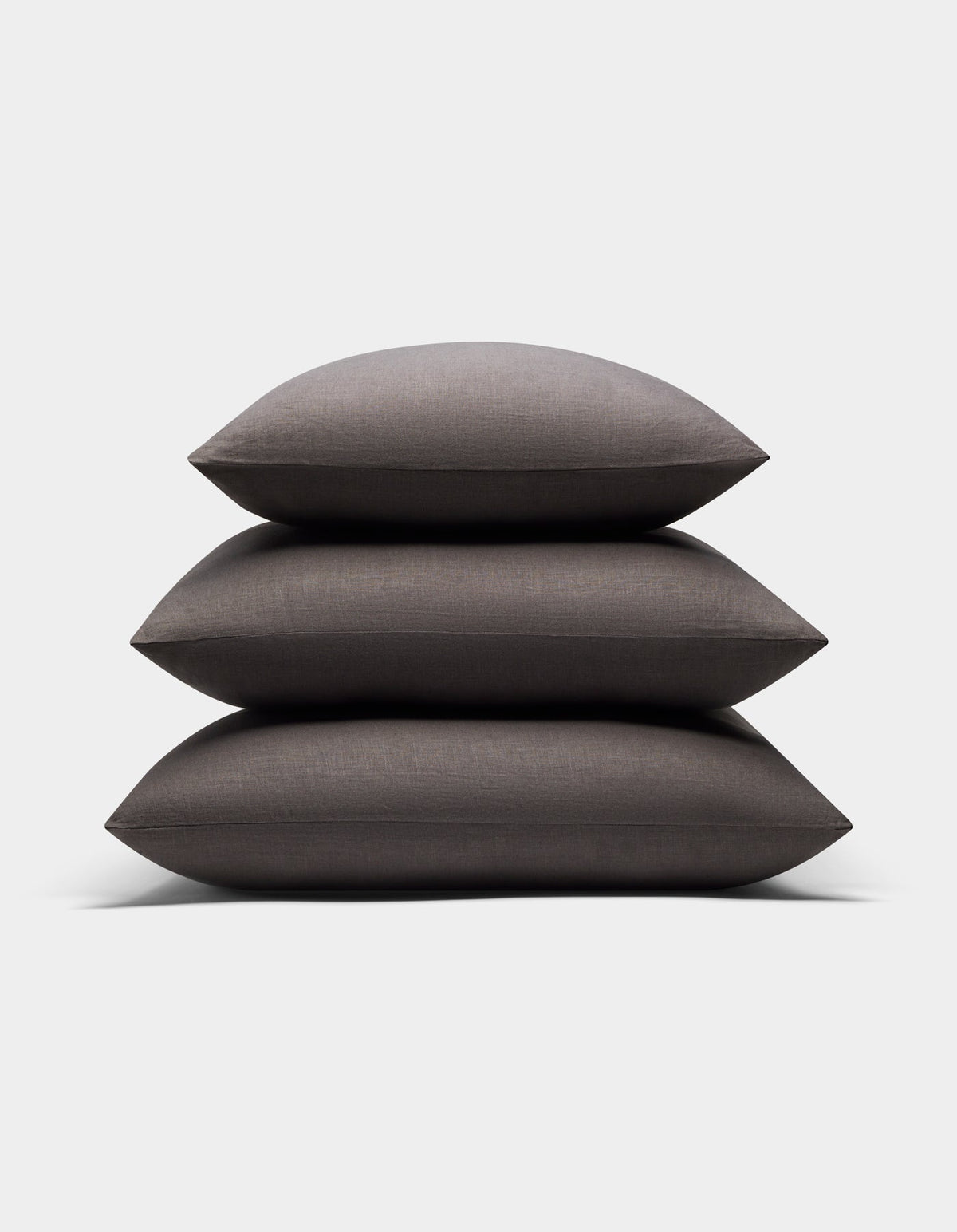Three Cozy Earth Linen Throw Pillows in dark gray are neatly stacked together against a plain white background.|Color:Coal|Size:20" x 20"