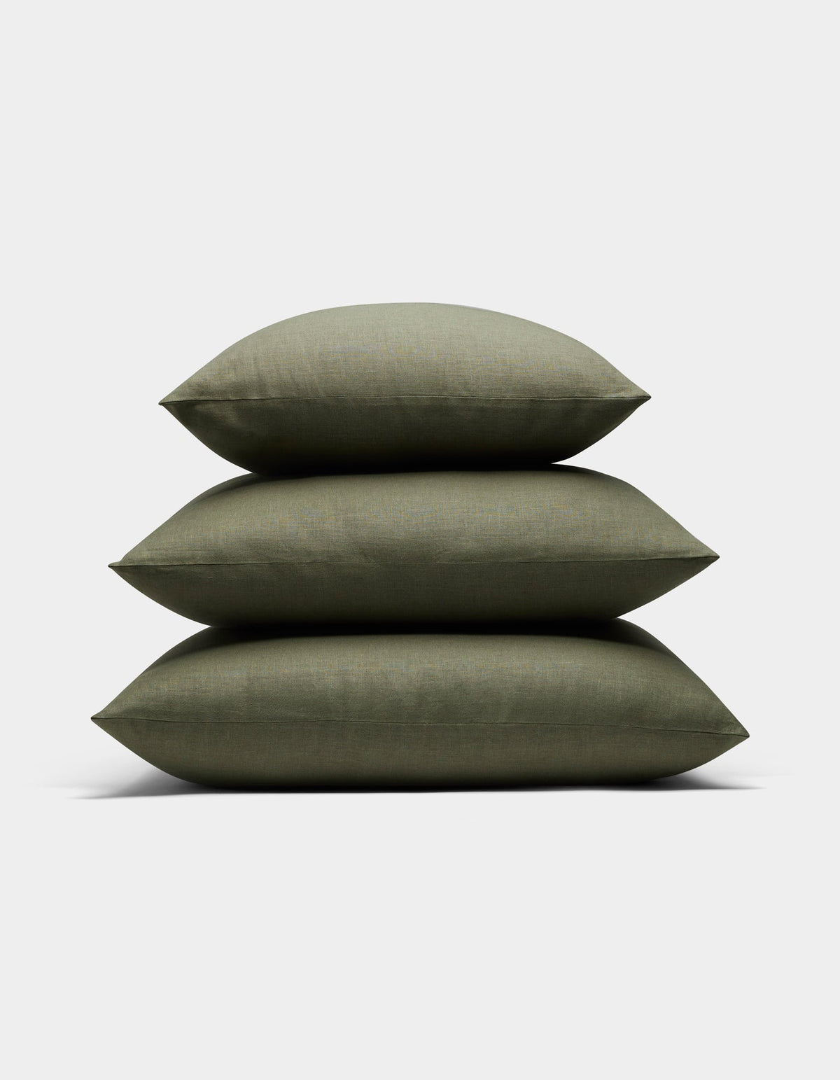 Three Cozy Earth Linen Throw Pillows in olive green are stacked neatly against a plain white background.|Color:Olive |Size:20" x 20"