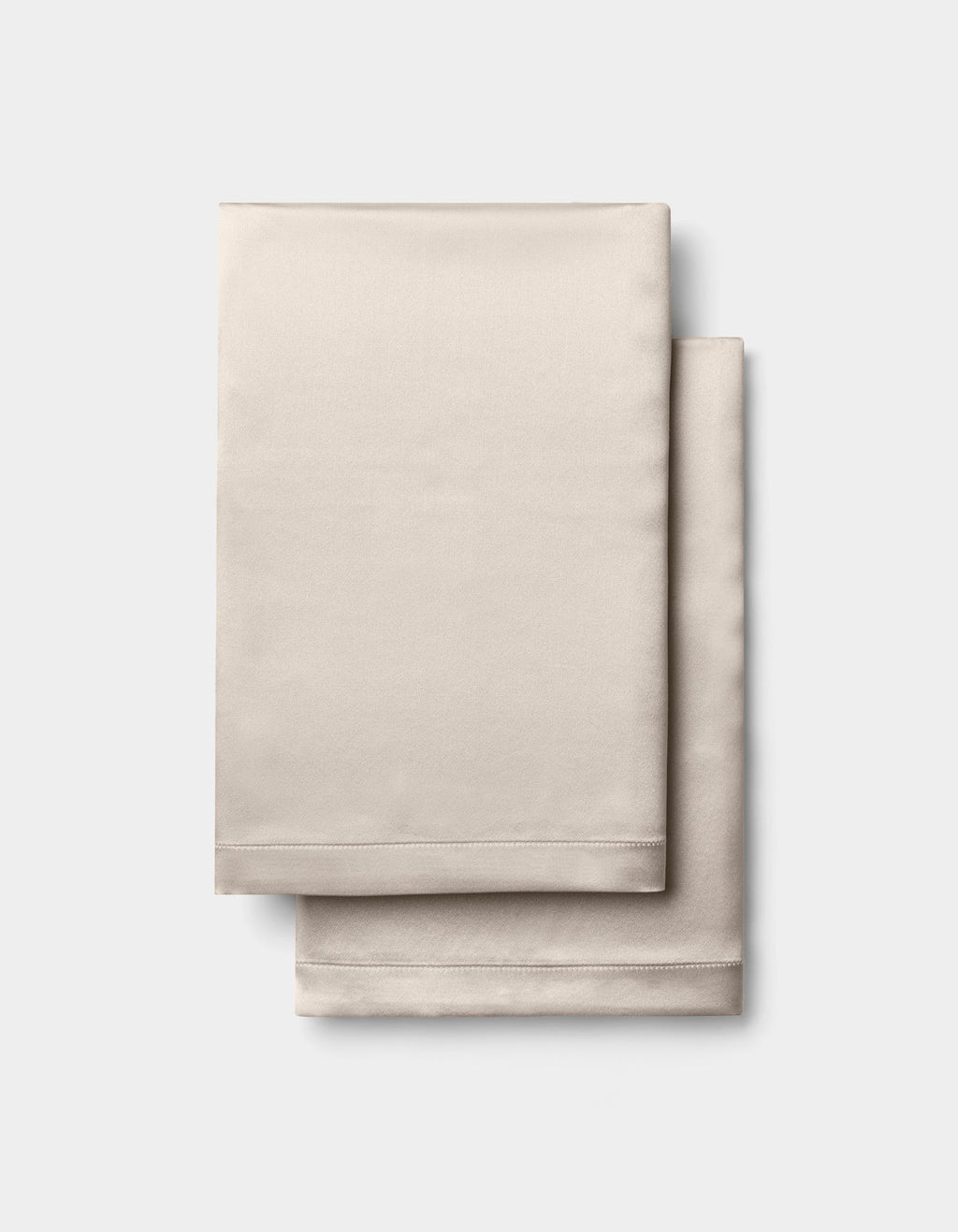 Two neatly folded Cozy Earth Silk Pillowcases in beige, stacked together against a plain white background.|Color:Driftwood