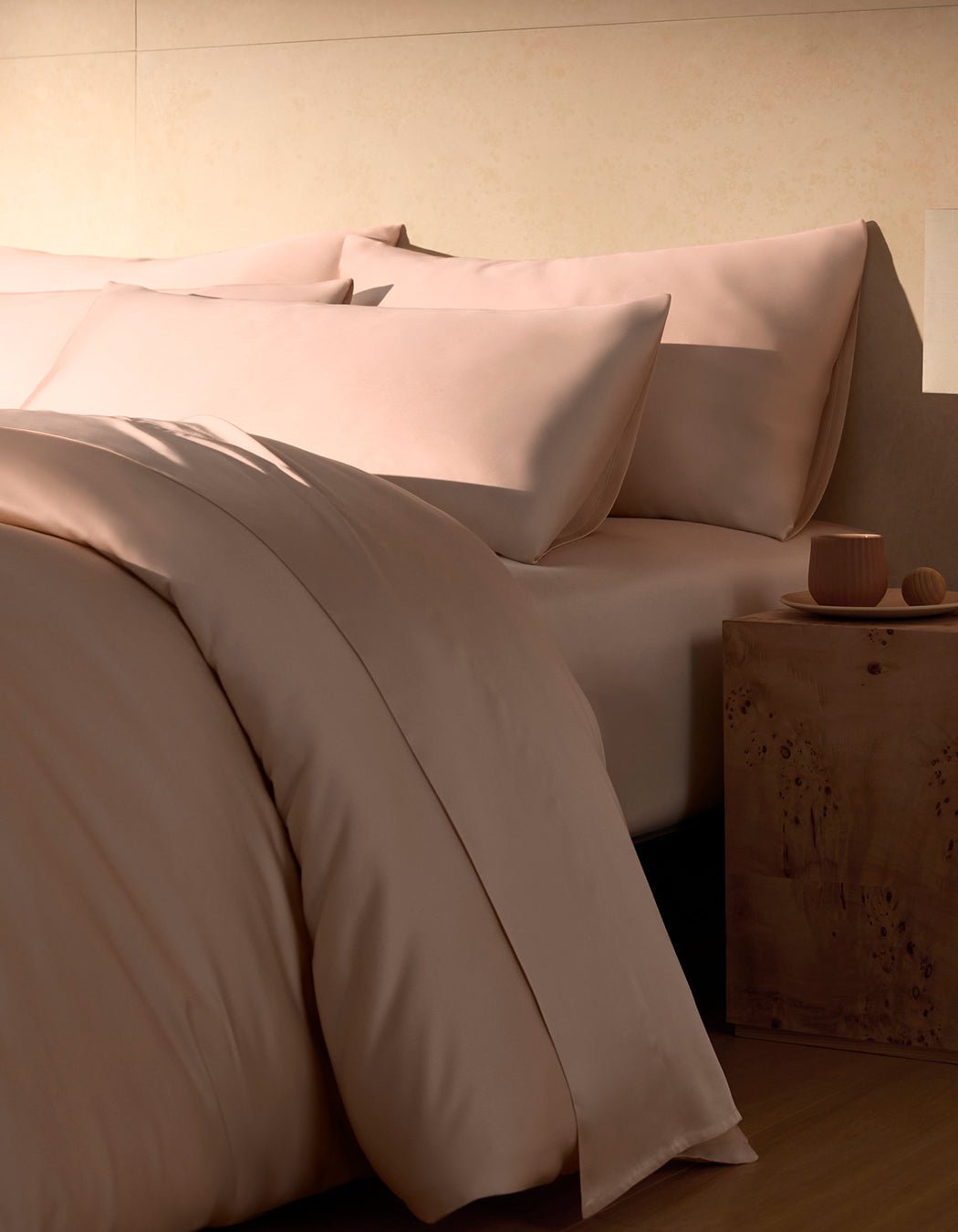A close-up view of a neatly made bed with pink Bamboo Pillowcases by Cozy Earth, featuring a smooth, soft-looking fabric.|Color:Peony