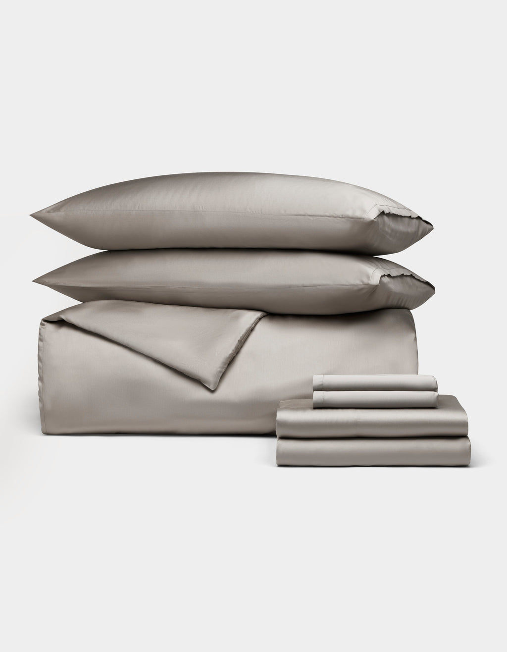 The Bamboo Bedding Ultimate Bundle by Cozy Earth features neatly stacked gray bed linens, including two pillows, a duvet, and folded sheets, all displayed against a plain white background.|Color:Dove Grey