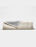 The Cozy Earth Baja Matelasse Coverlet features a neatly folded design with a cream side adorned with subtle lines and a textured gray reverse, shown against a plain white background.|Color:Alabaster/Oceanside