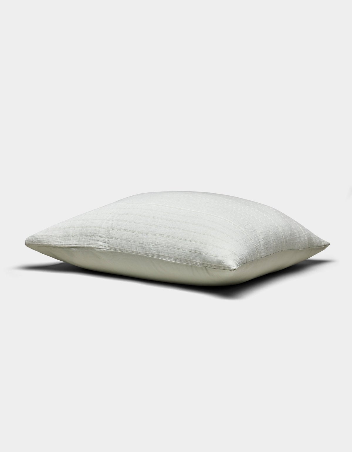 The Baja Matelasse Sham by Cozy Earth, shown in white with a smooth, subtly textured surface, is displayed horizontally against a plain light gray background.|Color:Bone/Laurel