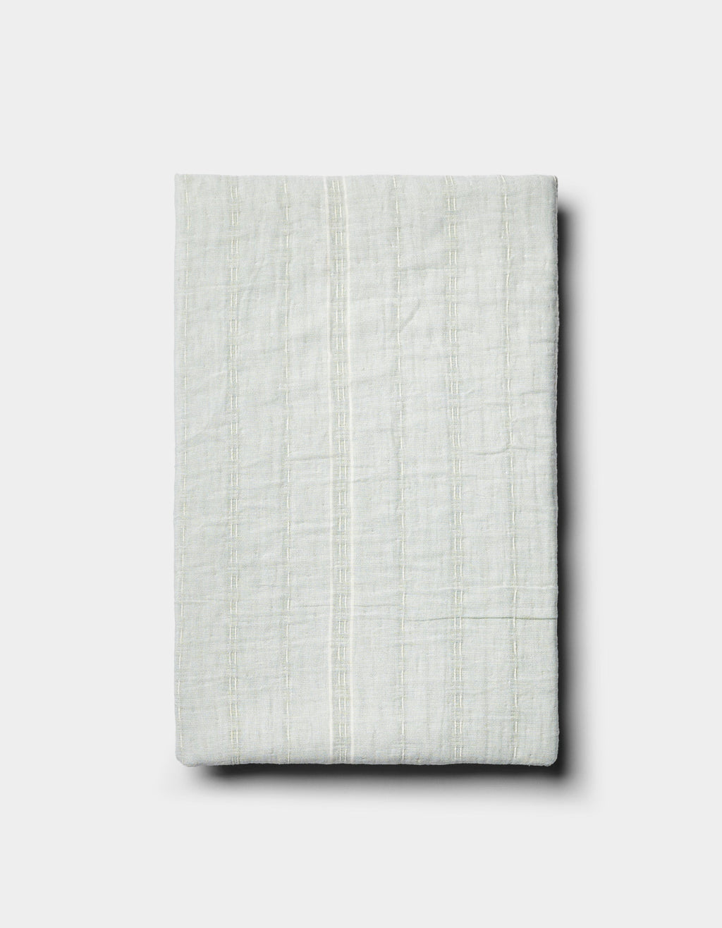The Baja Matelasse Sham by Cozy Earth is a neatly folded, light-colored textured fabric with subtle vertical stripes, displayed on a plain white background.|Color:Bone/Laurel
