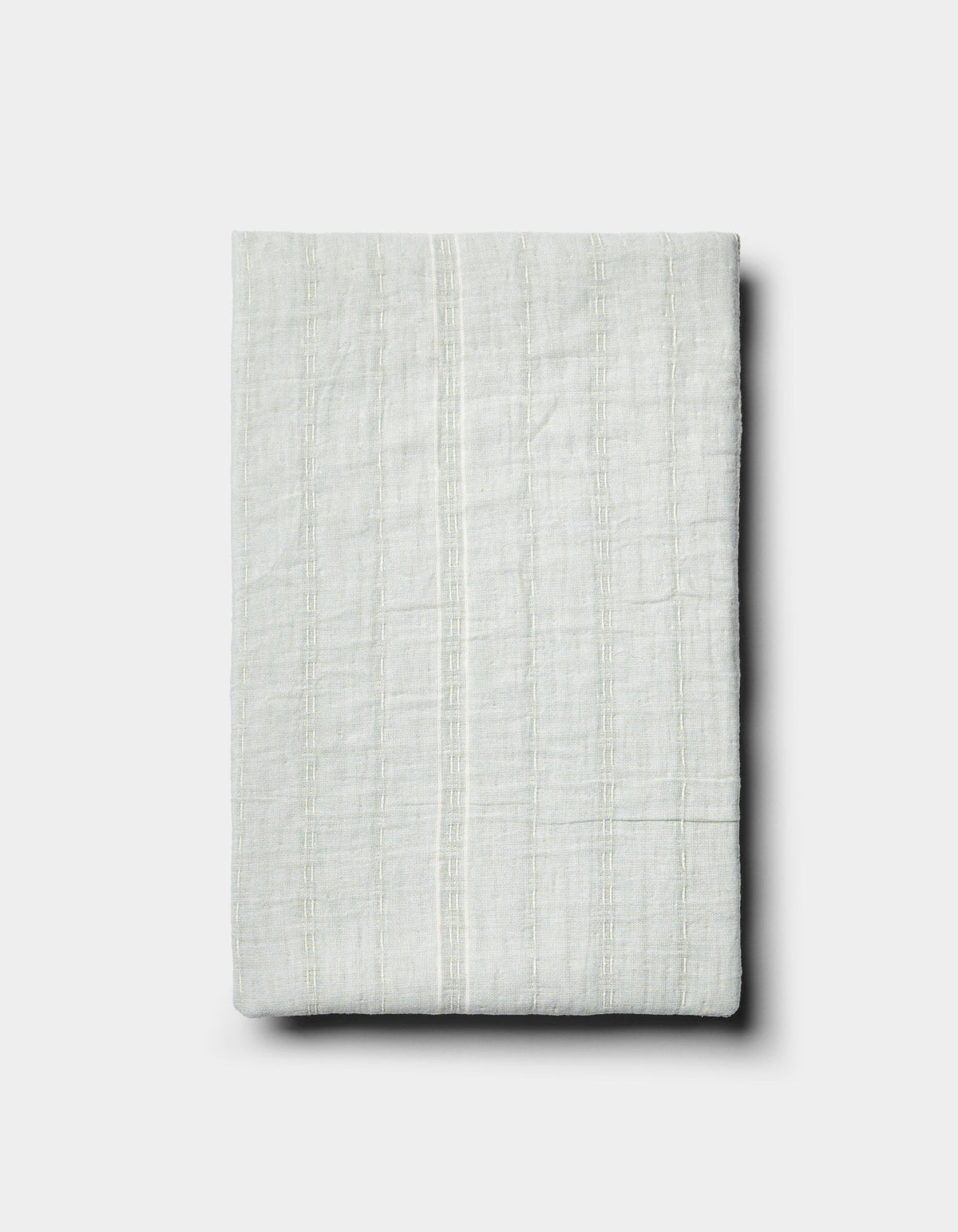 The Baja Matelasse Sham by Cozy Earth is a neatly folded, light-colored textured fabric with subtle vertical stripes, displayed on a plain white background.|Color:Bone/Laurel