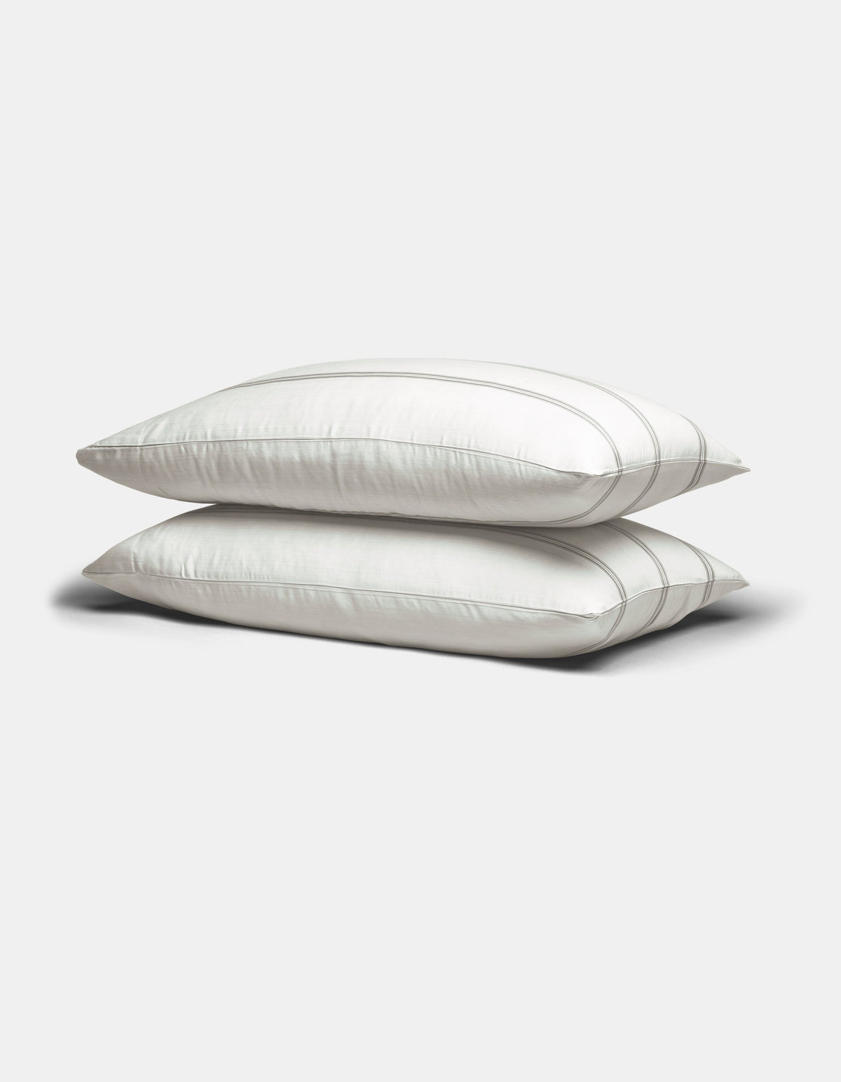 Two Cozy Earth Bamboo Pillowcases in white with subtle gray stripes are stacked on a plain light gray background.|Color:Baja Stripe in Laurel