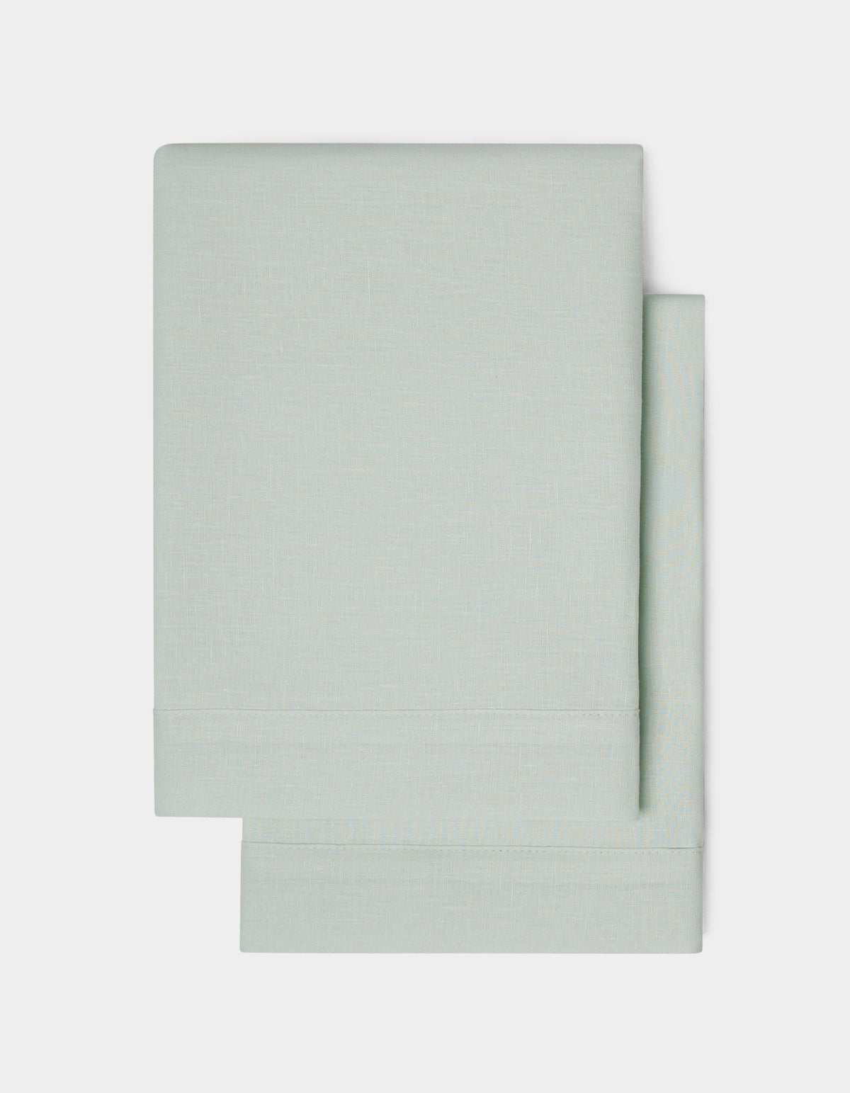 Two neatly folded Linen Shams by Cozy Earth in light gray are stacked on a plain white background, highlighting their simple and clean design.|Color:Mist