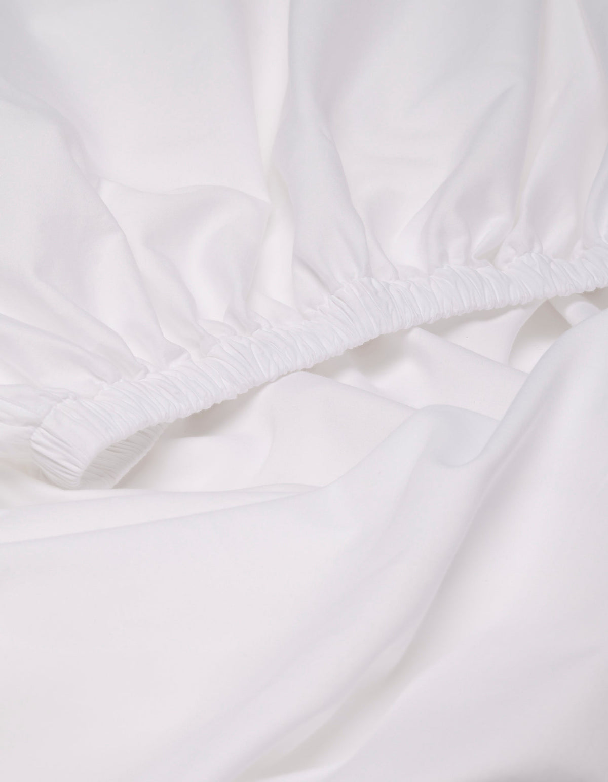 Close-up of the Cozy Earth Soft-Wash Cotton Fitted Sheet, featuring elastic edges, gathered fabric, and a smooth surface.|Color:White