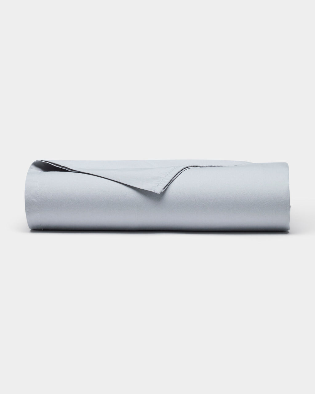The Soft-Wash Cotton Sheet Set by Cozy Earth is shown neatly rolled up in light gray on a plain white background, with one corner gently lifted.|Color:Shore
