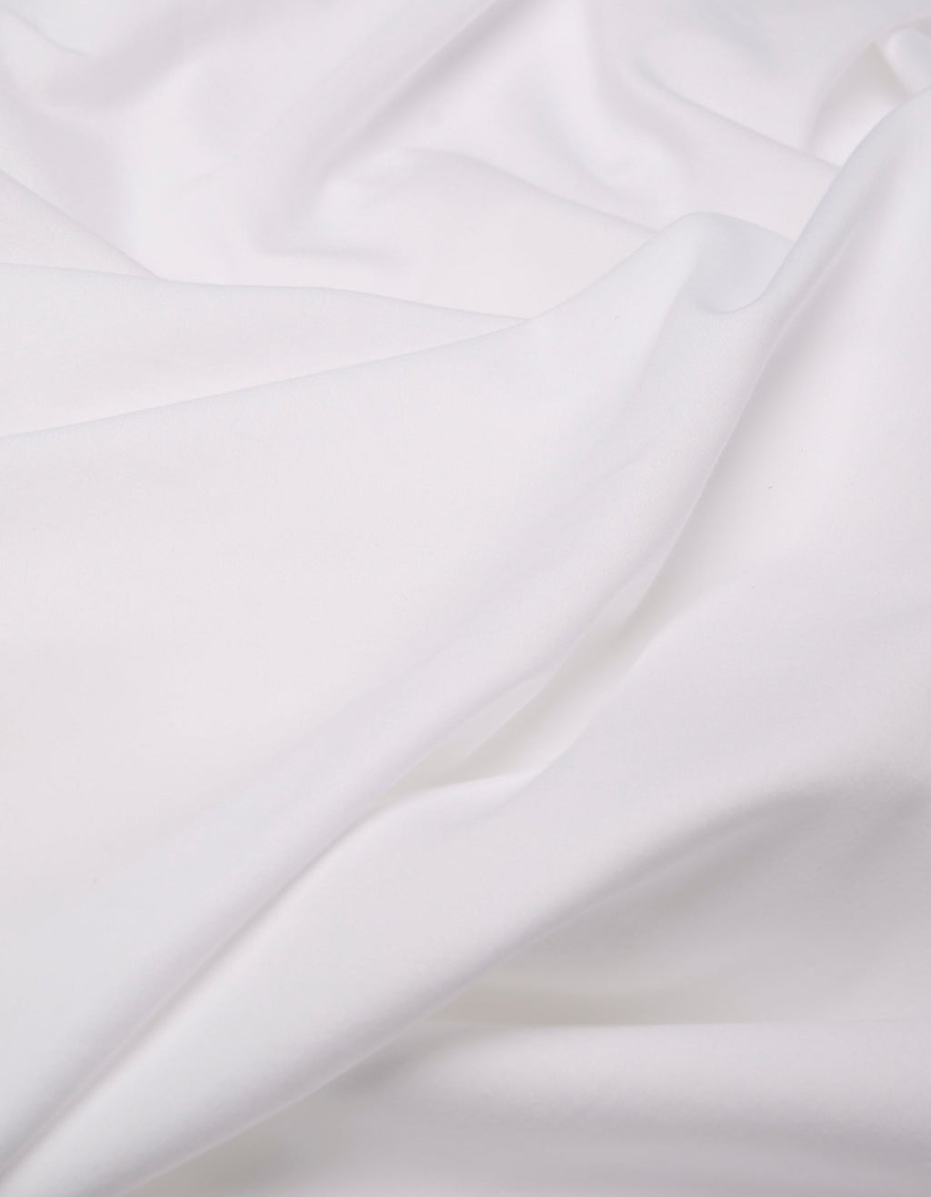 A close-up of the Cozy Earth Soft-Wash Cotton Flat Sheet shows white fabric with soft folds and gentle creases, creating a smooth, flowing texture.|Color:White